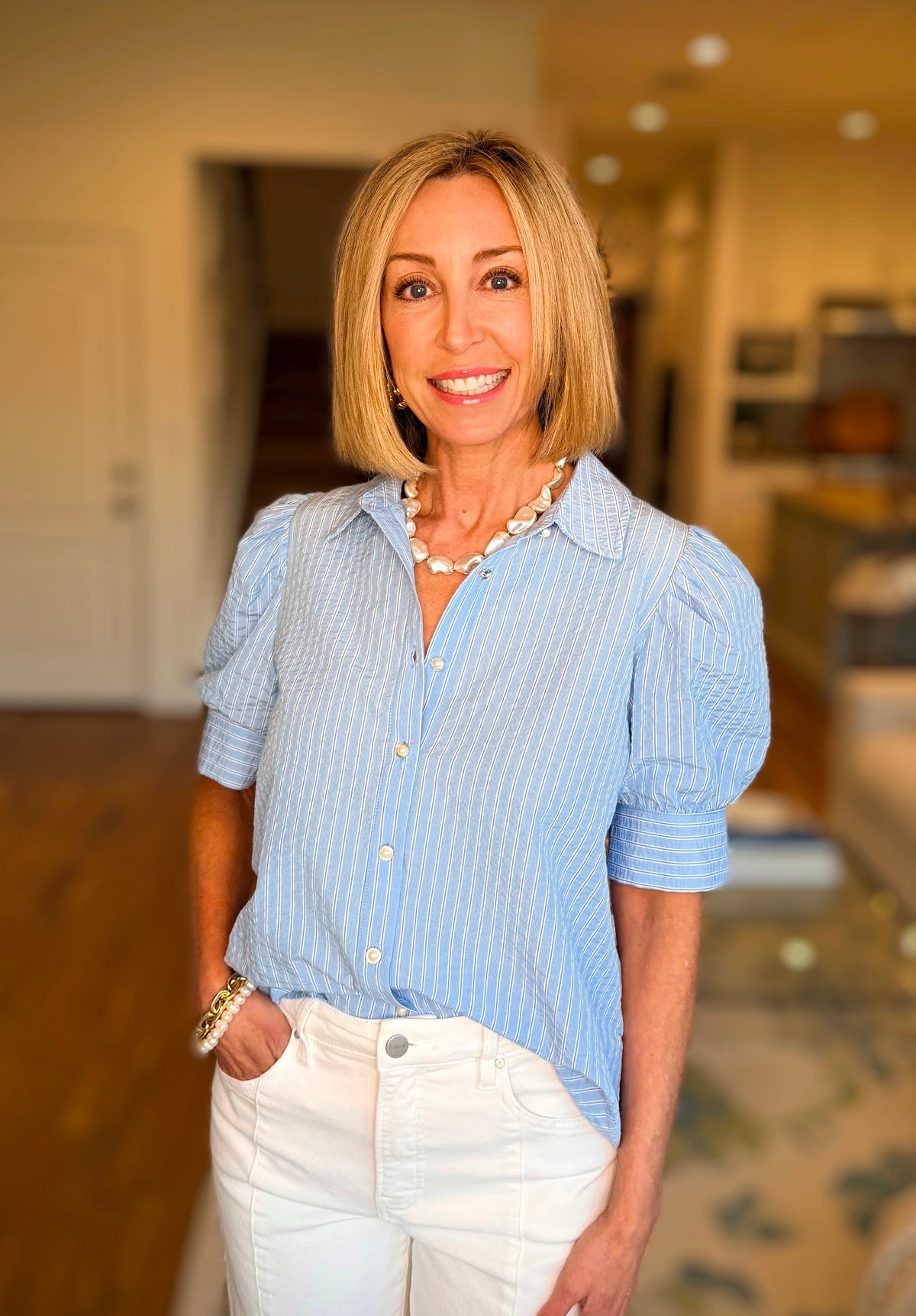 Woman wearing a blue striped shirt and white pants in an indoor setting