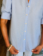 Person wearing a blue and white striped shirt with rolled-up sleeves.