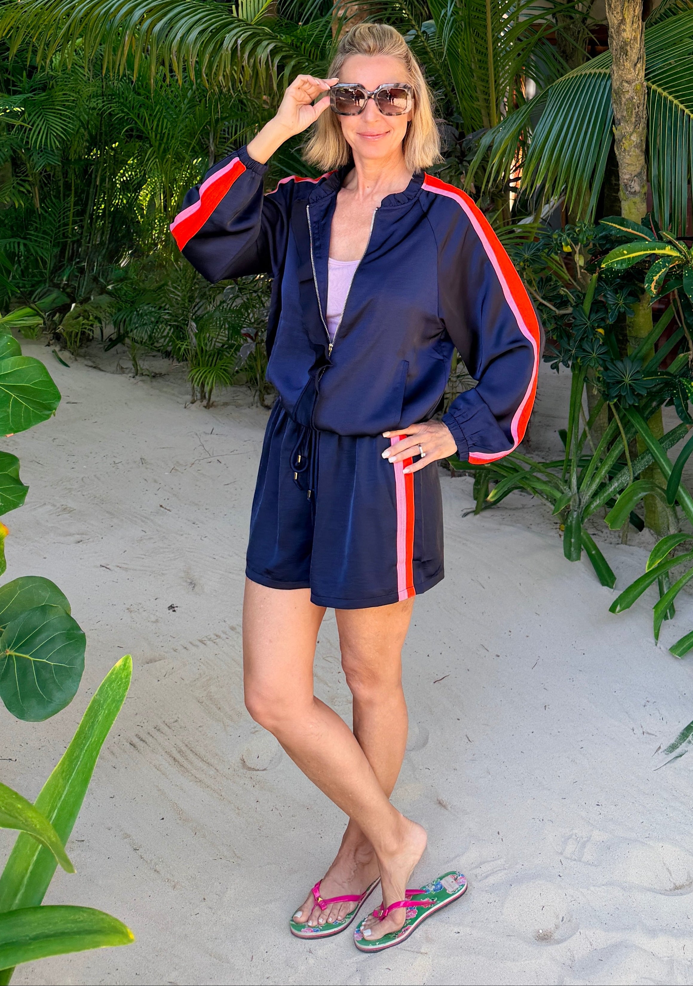 Woman in navy robe with red accents standing in a tropical setting